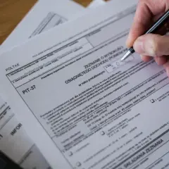 Ręka wypełnia PIT-37, szukając dodatkowego zwrotu z tytułu ulgi na dzieci.