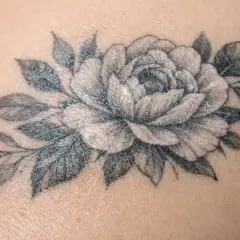 Un magnifique tatouage de pivoine et de feuilles, délicatement dessiné sur la peau.