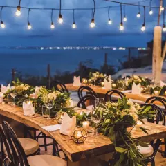 Tavoli apparecchiati per un magico matrimonio di sera, con luci soffuse e vista sul mare.
