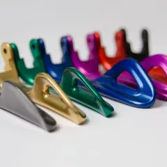 Una fila di moschettoni colorati, con finitura anodizzazione naturale, disposti su sfondo bianco.