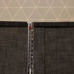 A ruler measures a dark grey cotton twill fabric. The fabric has a visible weave, characteristic of what is cotton twill.
