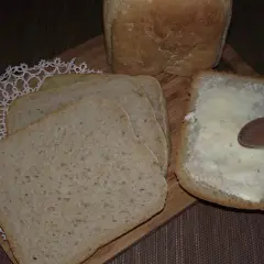 Chleb pszenno żytni na zakwasie, pokrojony w kromki. Jedna kromka jest posmarowana masłem.