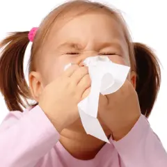 Bambina con raffreddore estivo, usa un fazzoletto per soffiarsi il naso.