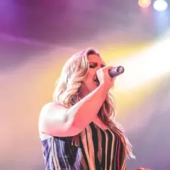 Cantante italiana sul palco, illuminata da luci soffuse. Immagina il suo cachet listino prezzi cantanti italiani.