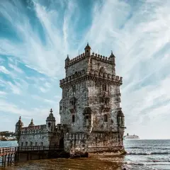 La Tour de Belém, un incontournable pour savoir que faire à Lisbonne, se dresse fièrement sur l'eau sous un ciel spectaculaire.