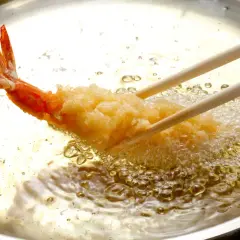 Krewetka w chrupiącej panierce panko smaży się na złoto w gorącym oleju.
