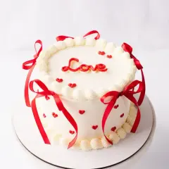 Uroczy tort bento ozdobiony czerwonymi serduszkami i wstążkami, z napisem "Love" na wierzchu. Idealny na Walentynki.