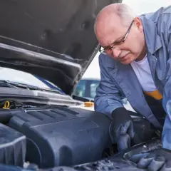 Mechanik sprawdza silnik, zastanawiając się, ile kosztuje wymiana chłodnicy w aucie.