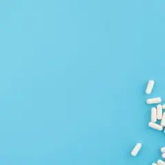 Białe kapsułki, jak lapixen, rozsypane na niebieskim tle.