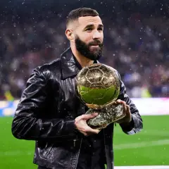 Karim Benzema trzyma Złotą Piłkę, zastanawiając się, ile waży złota piłka.