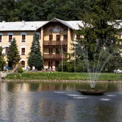 Piękny budynek sanatorium godne polecenia, z fontanną i stawem, otoczony zielenią.