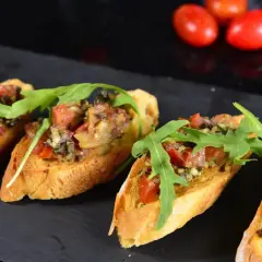 Czarujące tapas: chrupiące grzanki z pomidorami, ziołami i rukolą. Idealne na przekąskę, która rozbudzi apetyt.