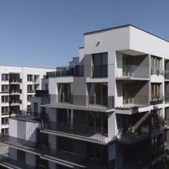 Nowoczesne bloki mieszkalne w city łobzów, z licznymi balkonami i dużymi oknami, na tle błękitnego nieba.