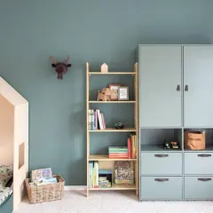 Gemütliches Kinderzimmer für Grundschulkinder mit Hausbett, Bücherregal und Spielzeug.