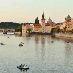 Widok na Wełtawę w Pradze, z licznymi łódkami i zabytkową architekturą. Idealne miejsce na wycieczkę z touroperatorem.