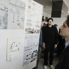 Ludzie oglądają wystawę projektów architektonicznych i makiety budynków.