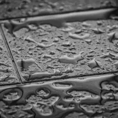 Gouttes d'eau sur un carrelage qui se décolle, signe d'une humidité persistante.