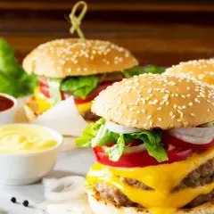 Tre succulenti burger roll con formaggio fuso, pomodoro, cipolla e lattuga, accompagnati da salse.
