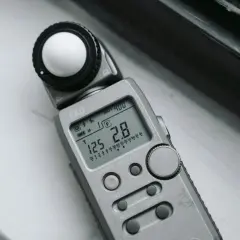 Srebrna jednostka oświetlenia EKO z kulistym dyfuzorem i wyświetlaczem pokazującym ISO 400, czas 125 i przysłonę 2.8.