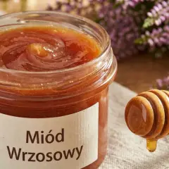 Słoik miodu wrzosowego, z którego kapie złocisty płyn, obok gałązka wrzosu. Miód wrzosowy właściwości zdrowotne.