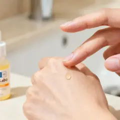 Una goccia di vitamina c siero a cosa serve? Illumina e idrata la pelle, applicata con cura su una mano.