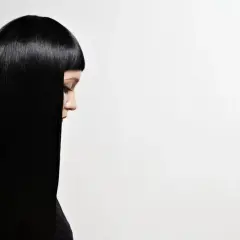 Perfil de mujer con cabello liso y brillante, negro azabache, cayendo sobre su hombro.