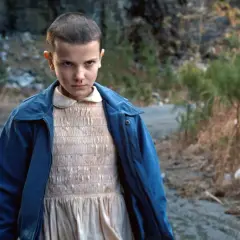 Nastka z Stranger Things, z nosem krwawiącym, stoi na brudnej drodze.