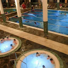 Widok na baseny termalne z jacuzzi i pływającymi ludźmi.