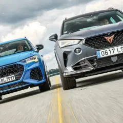 Niebieskie Audi RS Q3 i szare Cupra Formentor, dwa najlepsze SUV-y, pędzą po drodze.