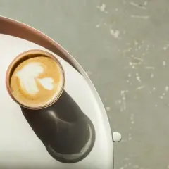 Idealny flat white z pianką w kształcie liścia, stojący na srebrnej tacy.