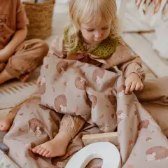 Mała dziewczynka bawi się śpiworem do przedszkola z motywem jeży.