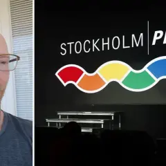 Man med glasögon och skägg framför en skärm med texten STOCKHOLM PRIDE och en regnbågsfärgad våg.