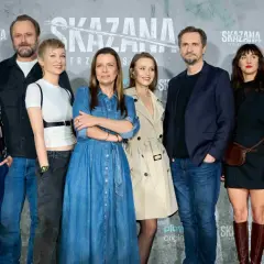 Skazana obsada na tle logo serialu. Grupa aktorów pozuje do zdjęcia, prezentując swoje stylizacje.
