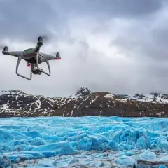Dron rejestruje spektakularne zdjęcia lodowca o intensywnie niebieskiej barwie, z ośnieżonymi górami w tle.