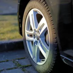 Zbliżenie na felgę aluminiową samochodu z widocznym logo Audi.
