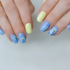 Delikatne kwiaty na paznokciach w pastelowych kolorach: błękitnym i żółtym. Wiosenny manicure z motywem stokrotek.