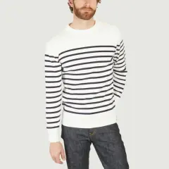 Un homme porte un pull marinière marin à rayures bleues et blanches, avec un jean brut.