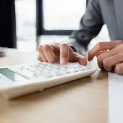Dłonie wpisują liczby na białym kalkulatorze. Obok leży dokument. Wiron 6m.
