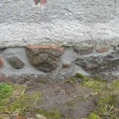 Frisch verfugtes Feldsteinfundament abdichten. Große Steine werden mit Mörtel verbunden, um das Mauerwerk zu schützen.