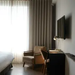 Przytulny pokój hotelowy z wygodnym łóżkiem, fotelem i biurkiem. Zastanawiasz się, ile kosztuje nocleg w takim miejscu?