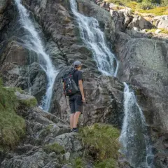 Turysta podziwia wodospad na jednym z tatrzańskich szlaków.