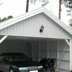 Vit carport på plintar med en bil och barnvagn.