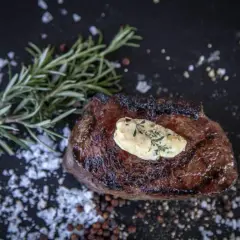 Perfekt medium gegrilltes Steak mit Kräuterbutter, Rosmarin und grobem Salz.