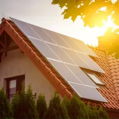 Panele fotowoltaiczne na dachu domu, symbolizujące przyszłość fotowoltaiki i zieloną energię. Słońce świeci jasno.