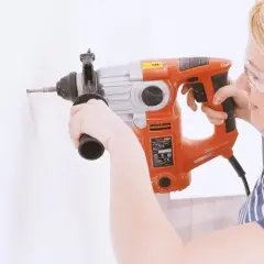 Femme avec lunettes de protection utilisant un marteau-perforateur pour percer du béton.