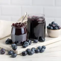 Słoiki z domowymi przetworami z borówki amerykańskiej, obok świeże owoce. Idealne na zimowe dni.