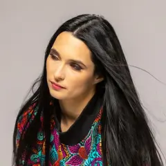 Portret kobiety z długimi, czarnymi włosami w kolorowej bluzce. Emilia Sanecka, data urodzenia.