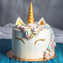 En hemmagjord tårta med enhörningstema, perfekt för barnkalas. Med en gyllene horn, färgglad frosting och gulliga ögon.