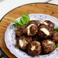 Köttbullar med ost, ett gott recept för viktnedgång gratis. Serveras på en vacker blåvit tallrik med basilika.
