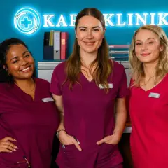 Drei Krankenschwestern lächeln vor dem Schild "Klinik". Staffel 12 von Bettys Diagnose verspricht spannende Fälle.